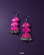 A pair of Parvaaz pink drop earrings displayed against a soft purple backdrop, highlighting the delicate floral motifs and showcasing their handcrafted detailing and graceful silhouette — Muselot.
