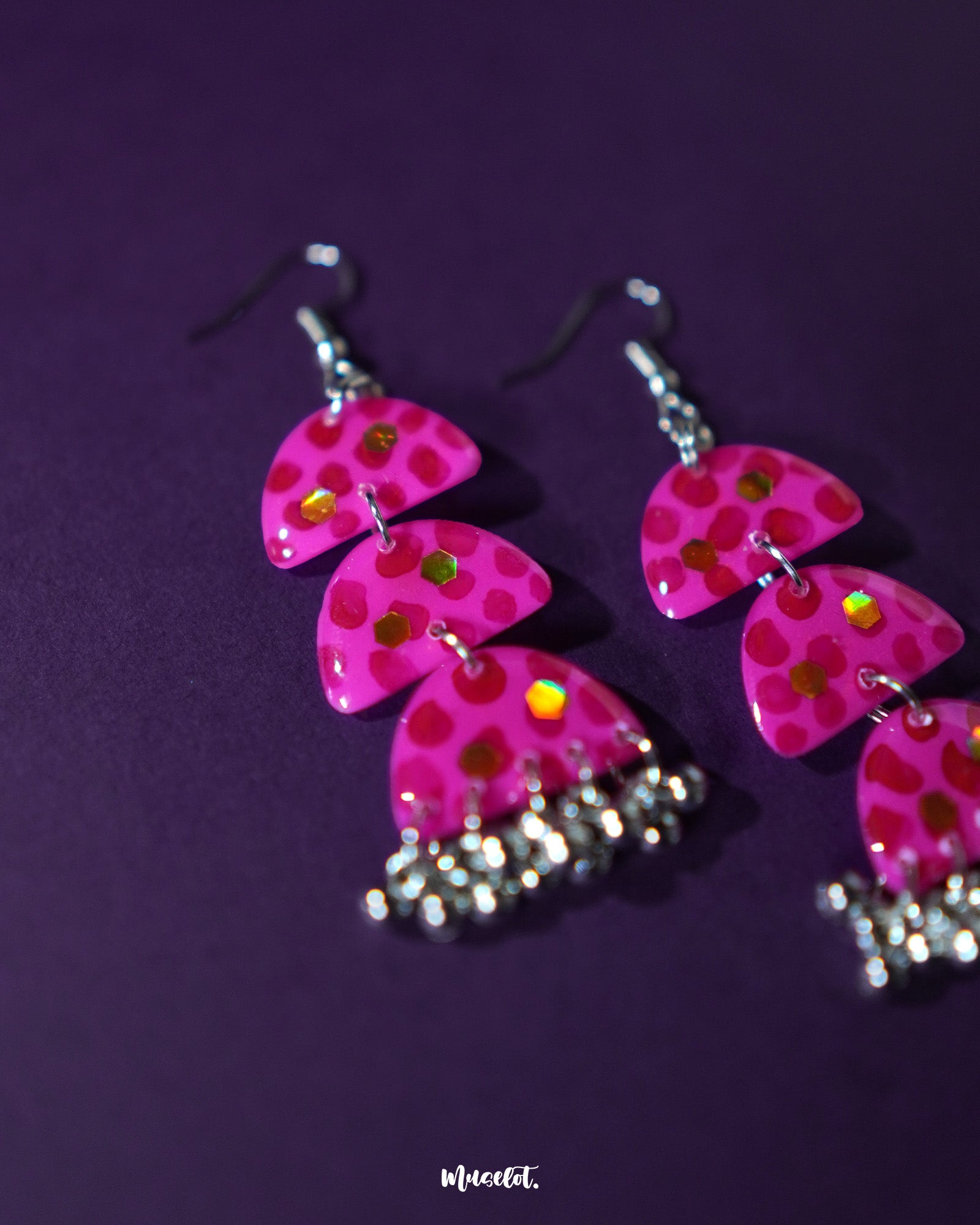 A detailed shot of Parvaaz pink drop earrings with delicately hand-painted petals and subtle shimmer, highlighting their elegant floral shape and showcasing the handcrafted finesse — Muselot.