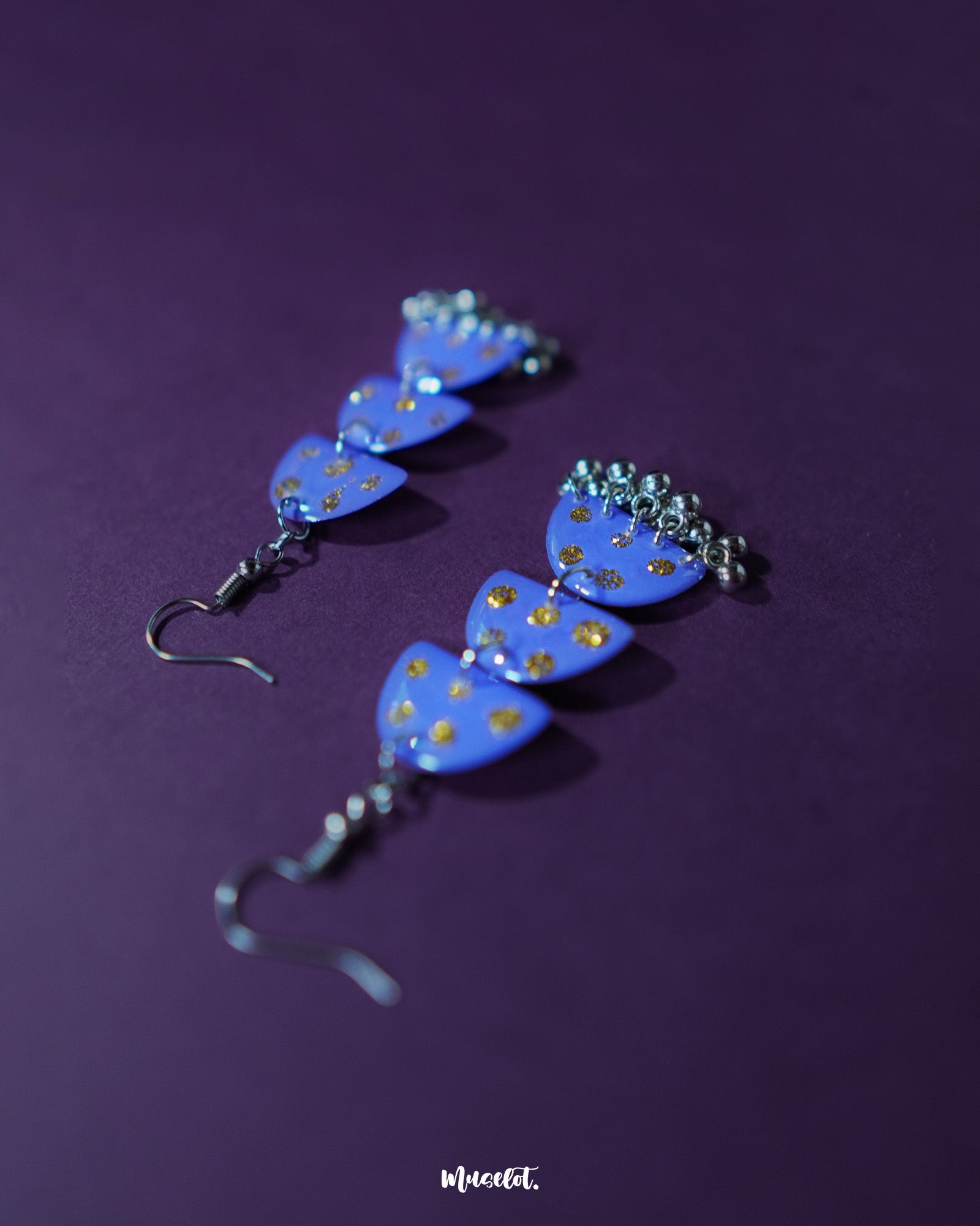 Parvaaz purple drop earrings displayed against a soft backdrop, showcasing their glossy finish and golden dotted accents that highlight the handcrafted finesse and vibrant color play — Muselot.