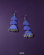 Parvaaz purple drop earrings displayed on a soft neutral surface, showcasing their handcrafted finish and shimmering golden dot accents that add a subtle festive flair — Muselot.