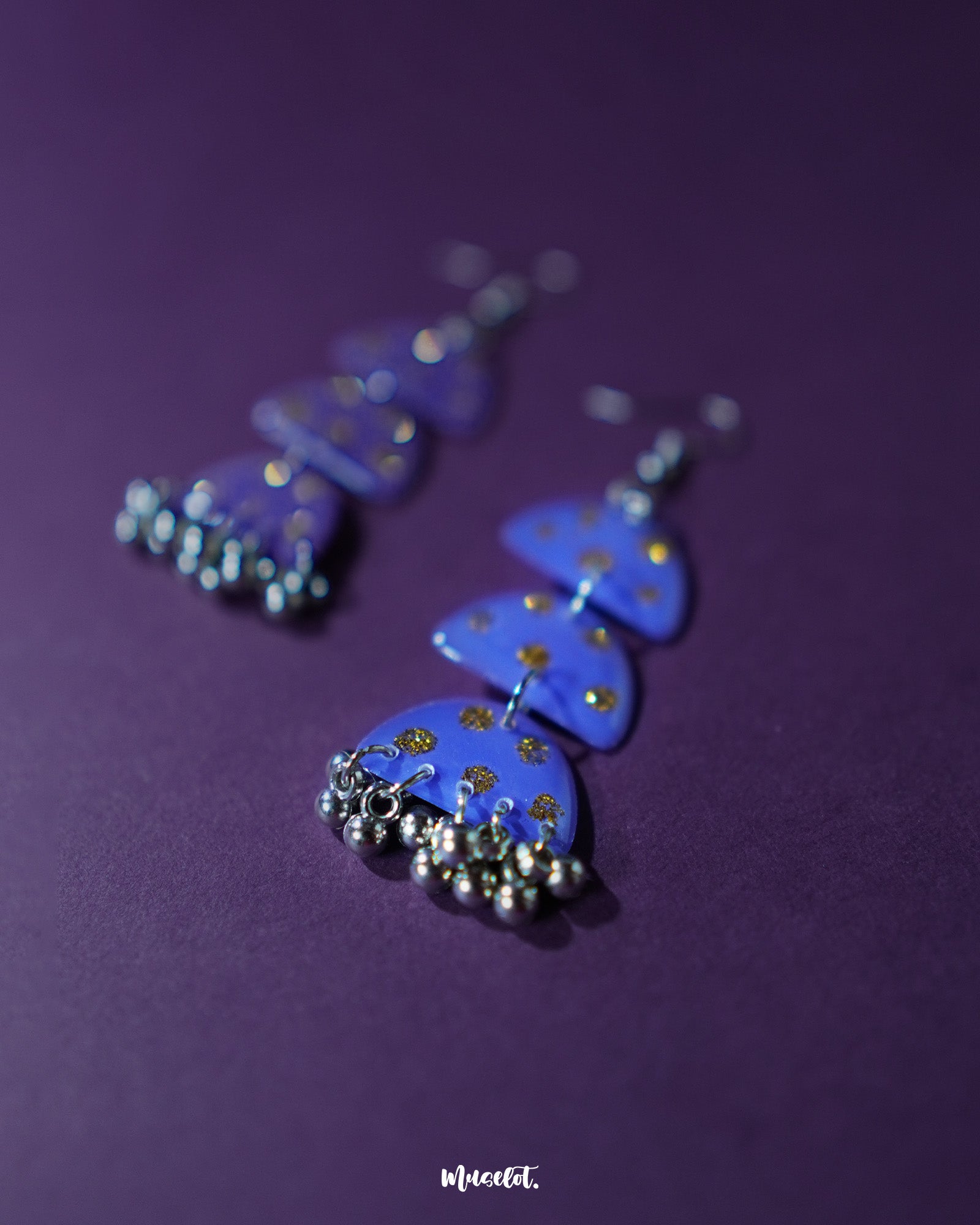A close-up of Parvaaz purple drop earrings featuring a smooth matte finish and delicate golden dots, highlighting the elegant teardrop shape and showcasing artisanal detailing with a rich, boho-inspired appeal — Muselot.