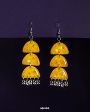 Parvaaz yellow drop earrings set against a deep purple background, featuring glossy hand-painted yellow domes with playful green accents and metallic danglers, highlighting vibrant energy and showcasing joyful craftsmanship — Muselot.