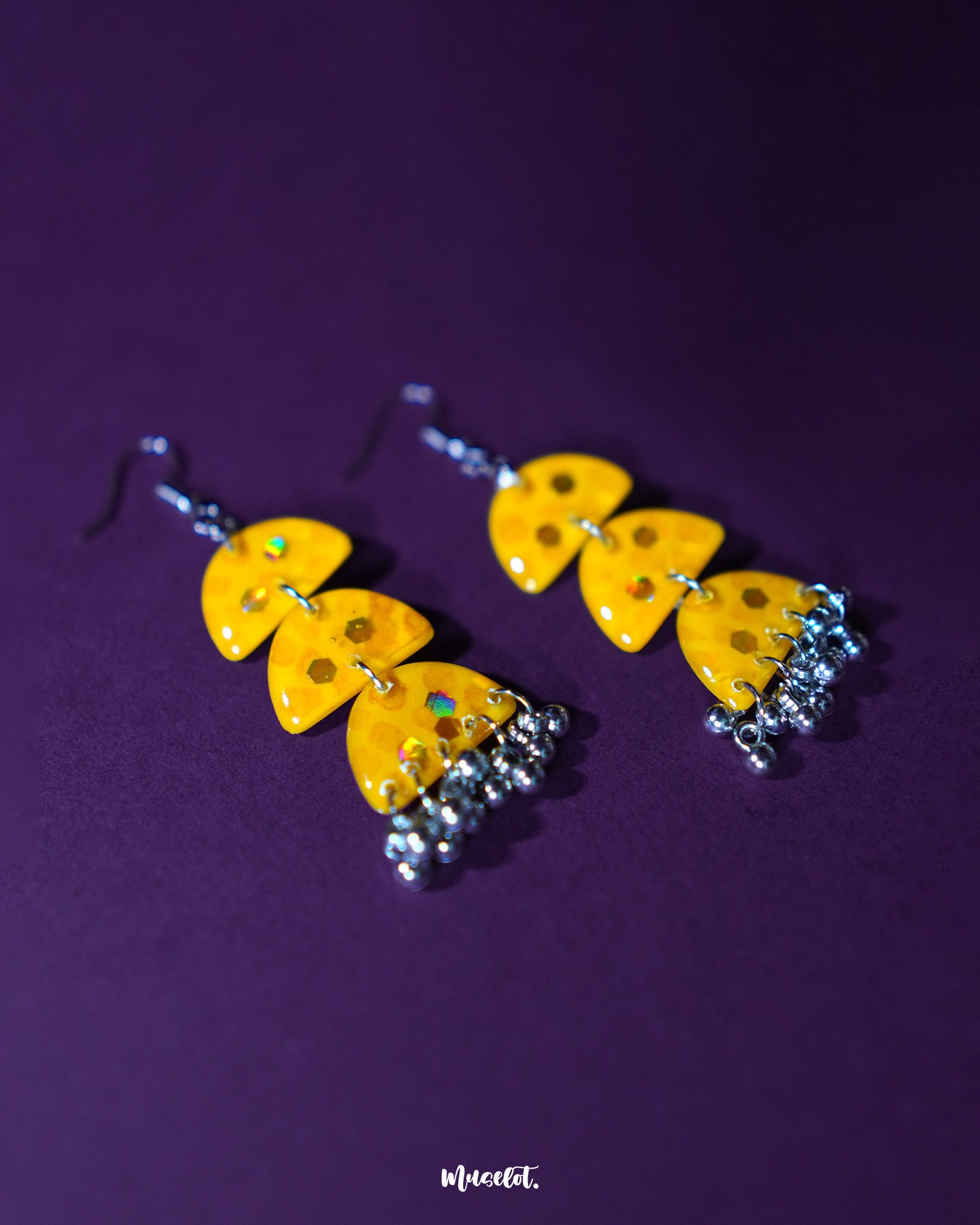 A close-up of Parvaaz yellow drop earrings featuring hand-painted floral details in warm hues, highlighting the bright, cheerful tone and showcasing their artisanal charm — Muselot.
