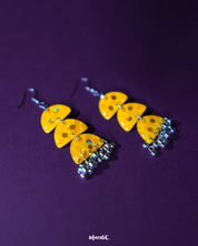 A close-up of Parvaaz yellow drop earrings featuring hand-painted floral details in warm hues, highlighting the bright, cheerful tone and showcasing their artisanal charm — Muselot.