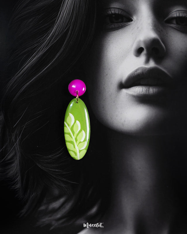 A close-up of the model wearing the Patbaan leaf drop earrings, highlighting the glossy green oval drops with delicate white leaf motifs and bold pink studs that bring out the earrings' handcrafted charm and vibrant character — Muselot.