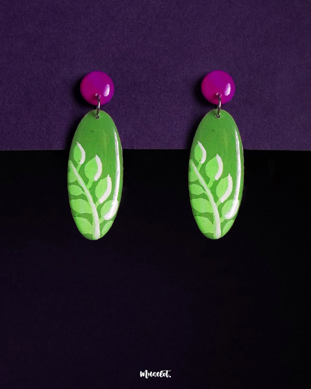 Patbaan leaf drop earrings in a vivid green base with hand-painted white leaf motifs, paired with a striking pink top stud — a bold, botanical-inspired accessory crafted to make a vibrant statement — Muselot.