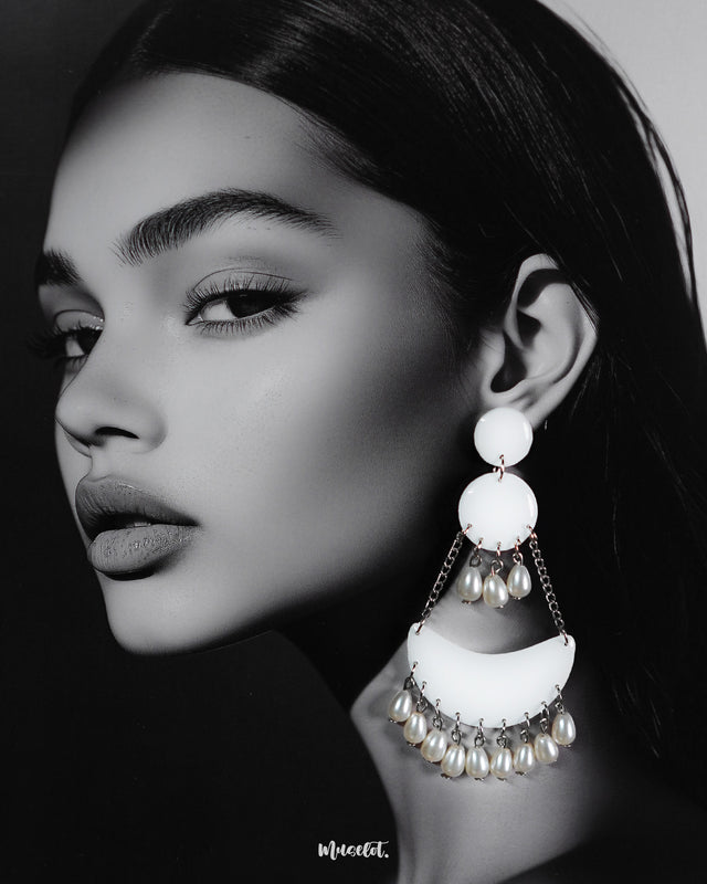 A woman wearing pearl handmade chandbali earrings, showcasing their crescent-shaped white base with dangling pearls and delicate silver chains, highlighting the serene charm of artisanal jewelry — Muselot.