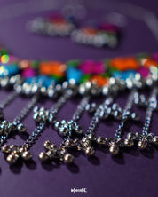A zoomed-in shot of the Rangbaagh black floral necklace set, highlighting the intricate silver gungroo chain that adds a rhythmic charm and traditional elegance to the overall handcrafted design — Muselot