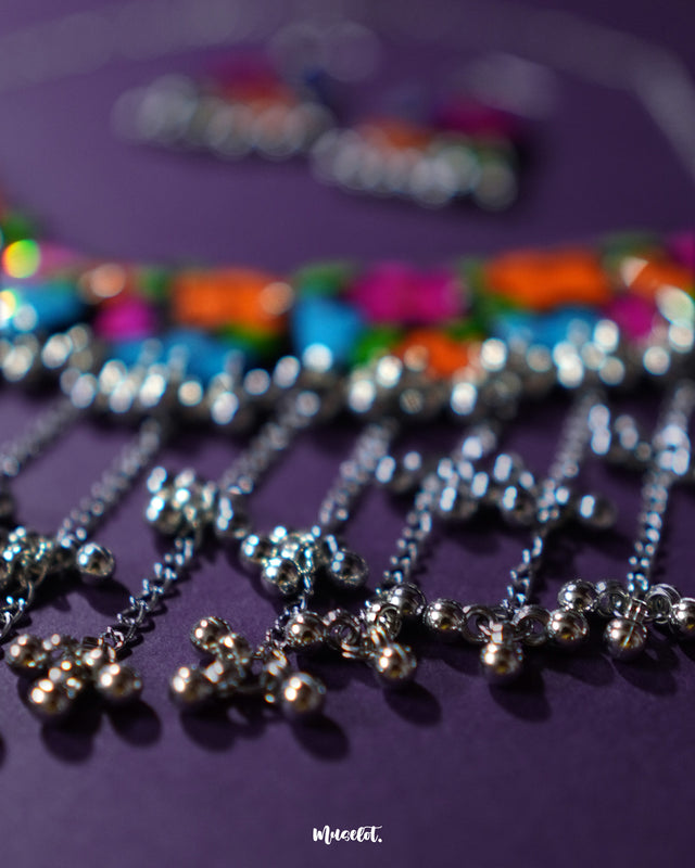 A zoomed-in shot of the Rangbaagh black floral necklace set, highlighting the intricate silver gungroo chain that adds a rhythmic charm and traditional elegance to the overall handcrafted design — Muselot