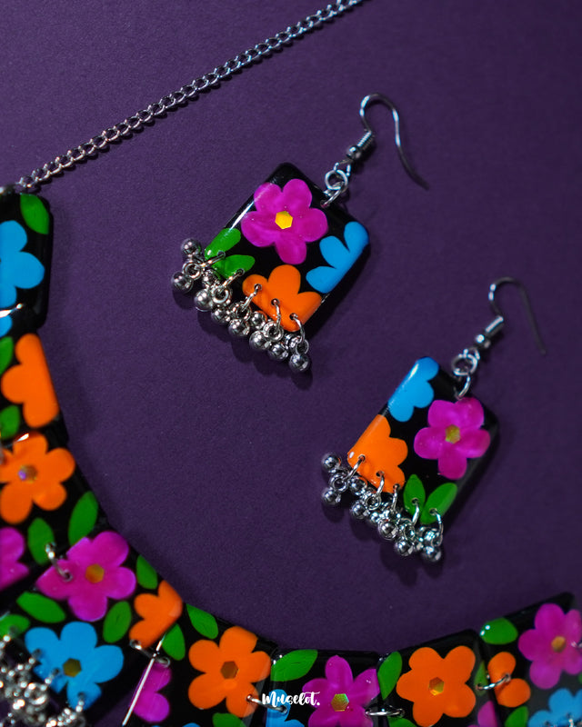 A close-up shot of the Rangbaagh black floral necklace set, highlighting its multicolored floral elements and intricate handcrafted design, paired with metallic gungroo detailing that adds a touch of traditional elegance — Muselot.