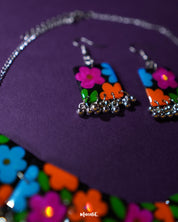 A close-up view of the Rangbaagh black floral earrings featuring delicately handcrafted blooms in vibrant blue, orange, and purple shades, paired with intricate silver detailing that brings a playful yet traditional charm — Muselot.