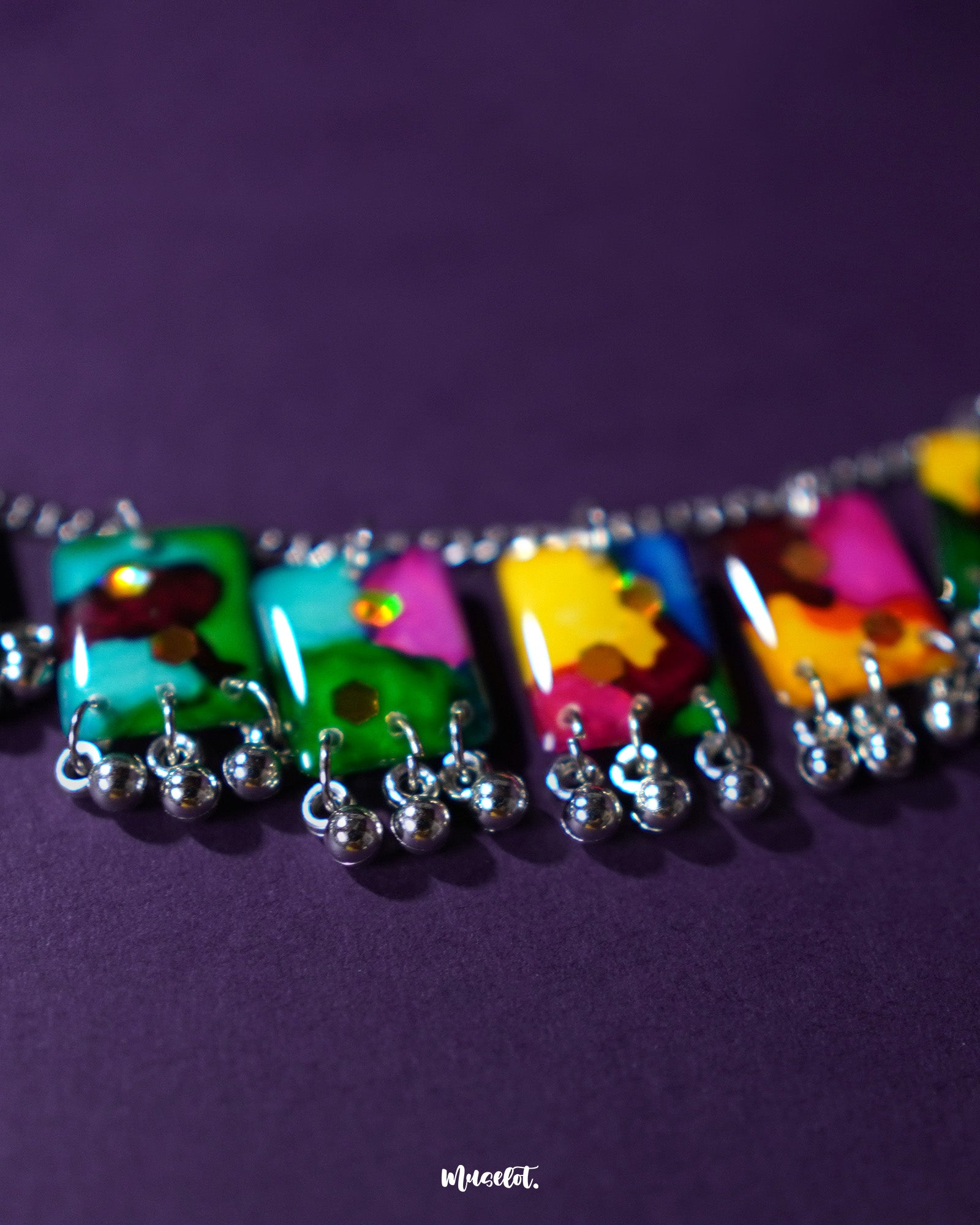 Zoomed-in view of the Rangbaari colorful jewelry set, showcasing the detailed multicolor abstract patterns on rectangular charms with silver bead accents, capturing the vibrant artistry and fine craftsmanship – Muselot.