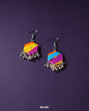 A pair of Rangbahaar colorful hook earrings displayed against a purple background, featuring a striking mix of orange, yellow, pink, and blue hues with hexagonal sequin details and silver-toned dangling beads for a playful, handcrafted charm — Muselot.