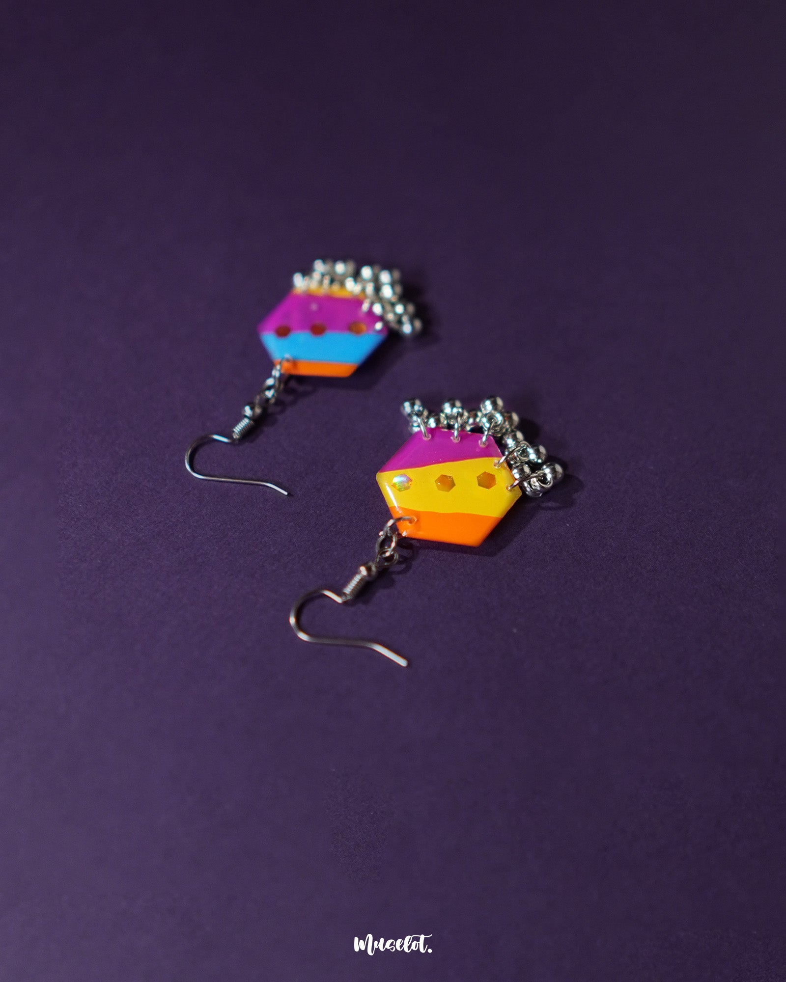 A pair of Rangbahaar colorful hook earrings placed on a neutral background, highlighting the intricate embroidery, mirror accents, and beaded fringes that celebrate vibrant Indian craftsmanship — Muselot.