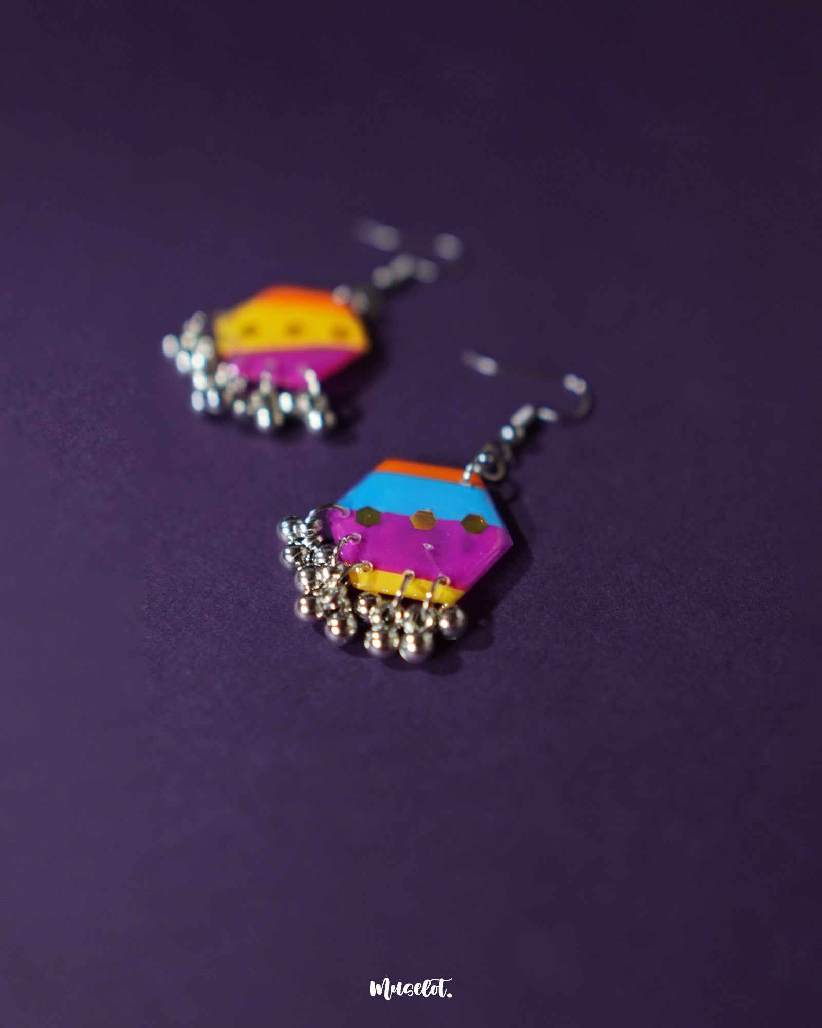 Rangbahaar colorful hook earrings displayed from a top angle, revealing the layered textures of thread embroidery, small mirrors, and dangling beads in a festive, handcrafted design — Muselot.