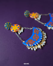 A closer look at the Ranglahar blue chandbaali earrings reveals the intricate enamel work and radiant blue crescent base, highlighted with vibrant orange detailing and dainty pearls. These handcrafted beauties strike the perfect balance between ethnic charm and contemporary color play — Muselot.
