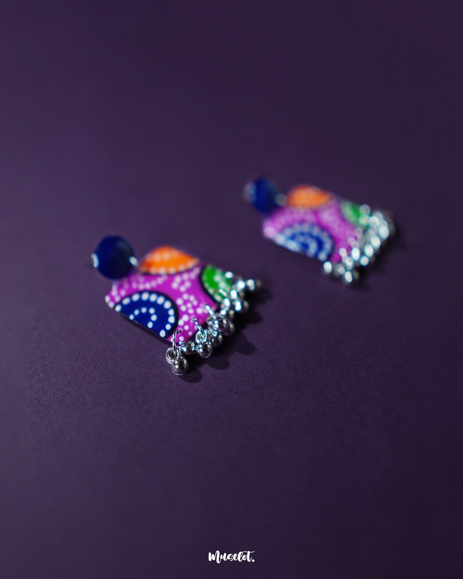 Rangras stud earrings, set against a rich purple background, featuring intricate folk art patterns and vibrant colors that showcase a perfect blend of traditional craftsmanship and modern elegance — Muselot.