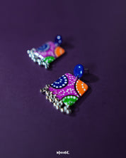Rangras stud earrings featuring intricate folk-art motifs in a vibrant palette, set against a soft backdrop that highlights their artisanal craftsmanship and bold expression — Muselot