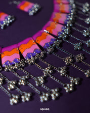The Rangrezan handmade colorful necklace set rests elegantly against a rich purple background, highlighting its intricate beadwork and vibrant hues that capture the spirit of folk artistry — Muselot.