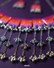A close-up view of the Rangrezan handmade necklace set highlights the playful cluster of ghungroos, their metallic charm adding a rhythmic, festive touch to the colorful beads and intricate threadwork — Muselot.