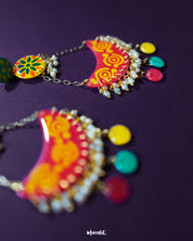 A close-up of the Rangsiya colorful chandbali earrings showcasing their vibrant red and yellow hand-painted detailing, delicate pearl drops, and playful multicolor danglers hanging from golden chains — Muselot.