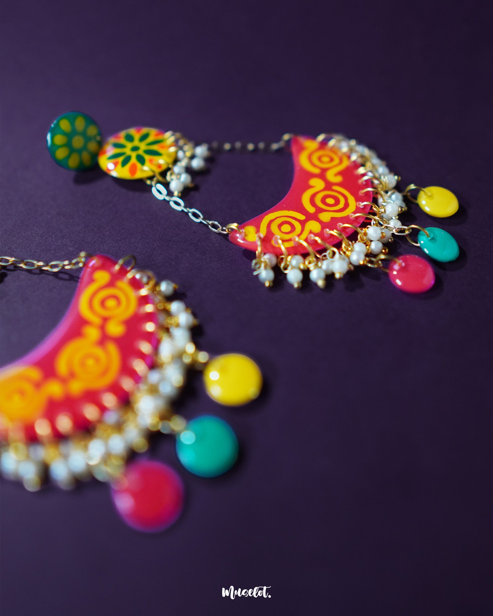 A close look at the Rangsiya colorful chandbali earrings reveals their fine craftsmanship — the hand-painted enamel work in bright red and yellow tones is beautifully complemented by the dainty pearl clusters and antique gold finish — Muselot.