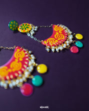 A close look at the Rangsiya colorful chandbali earrings reveals their fine craftsmanship — the hand-painted enamel work in bright red and yellow tones is beautifully complemented by the dainty pearl clusters and antique gold finish — Muselot.