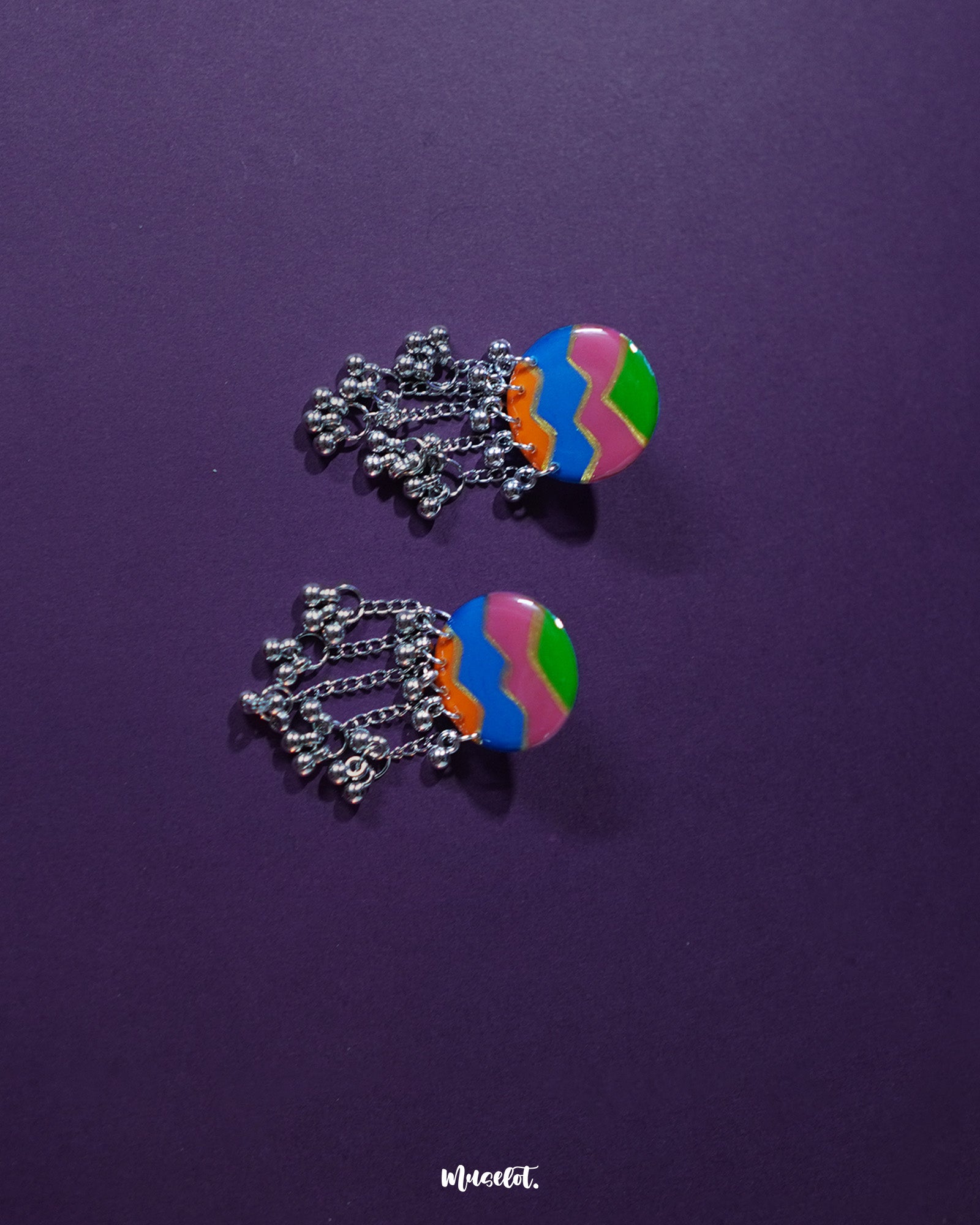 Rangtarang colorful long chain earrings showcasing a vibrant fusion of hand-painted zigzag patterns in green, pink, blue, and orange, paired with dangling silver chains and metallic beads that dance with every movement, capturing the essence of playful elegance – Muselot.