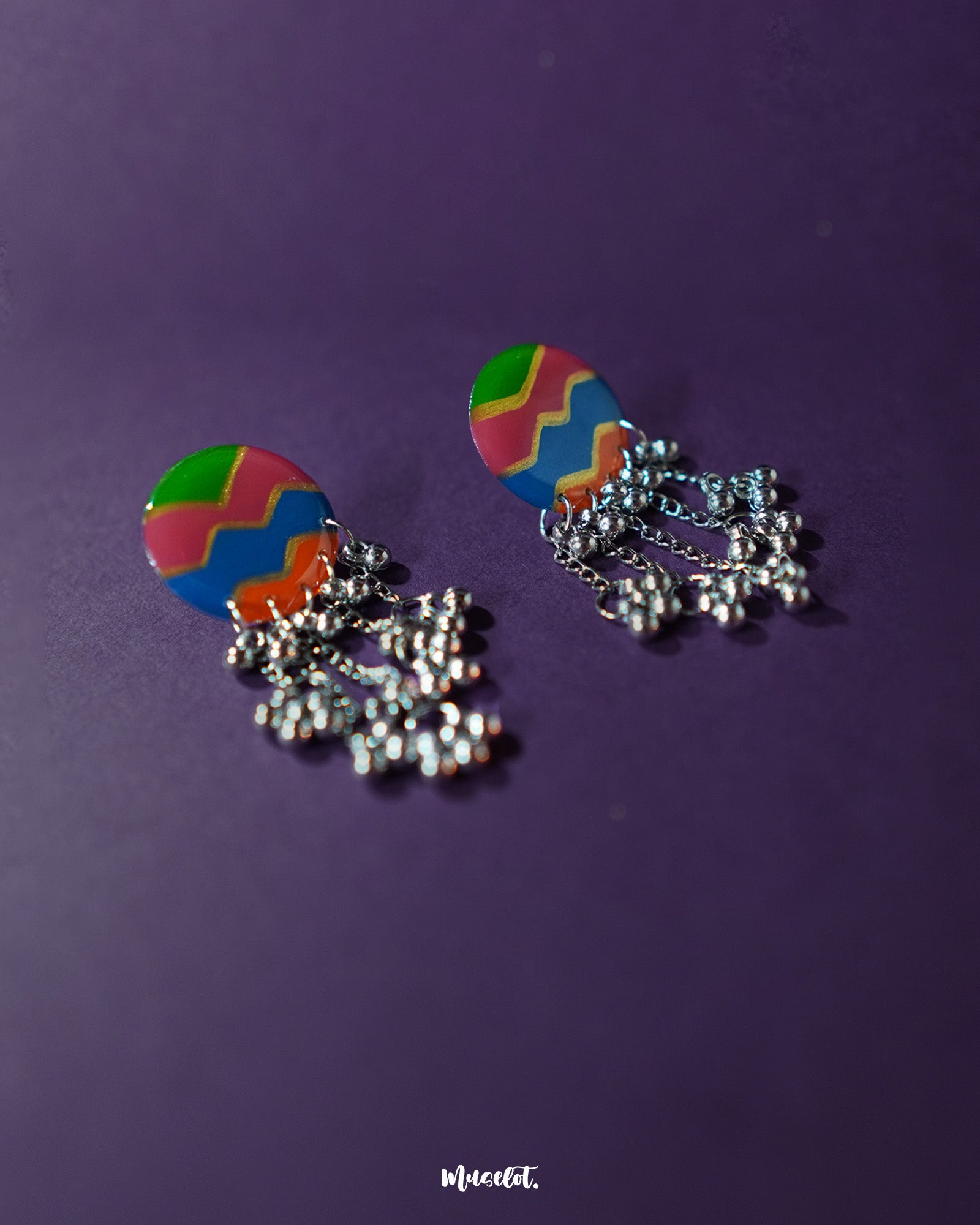 Rangtarang colorful long chain earrings shown resting against a rustic surface, highlighting the intricate hand-painted detailing and multicolor accents that add depth and charm to these statement earrings – Muselot.