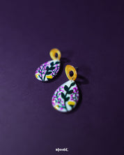 Close-up of Raushanbahaar floral drop earrings, capturing the teardrop shape adorned with pink and yellow hand-painted flowers and leafy accents, highlighting vibrant artistry and showcasing the intricacy of handmade design — Muselot.