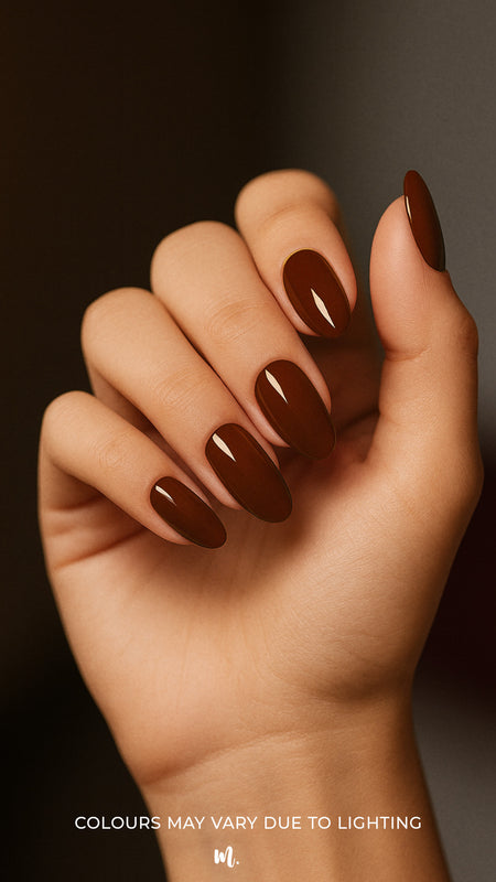 A shot of a model’s hand wearing Rich Cocoa nail stickies, showcasing the deep chocolate-brown shade with a sleek glossy finish, highlighting the bold yet elegant charm of minimal nail art in a refined salon-style look – Muselot.