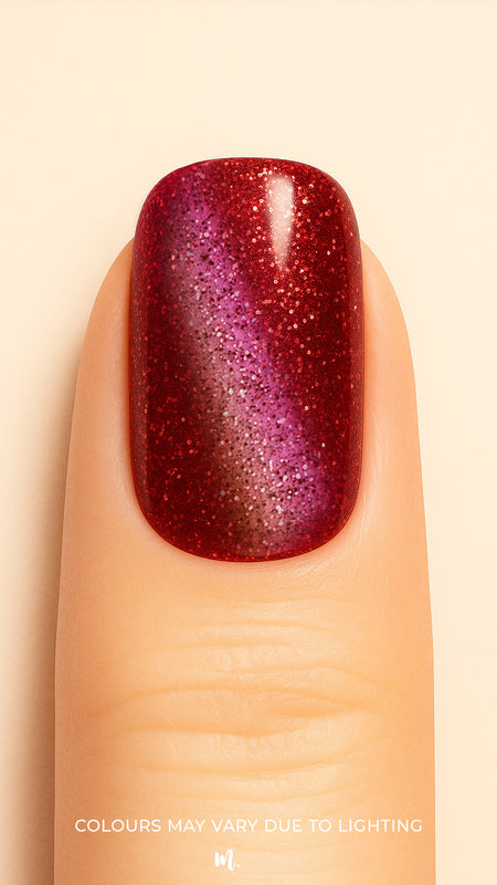 A close-up of a model’s finger wearing Romantic Ruby Cat Eye Nail Stickies, featuring a dazzling ruby-red base with a magnetic cat-eye shimmer effect that shifts into deep purple tones, enhanced with fine glitter sparkles for a bold and glamorous manicure – Muselot.