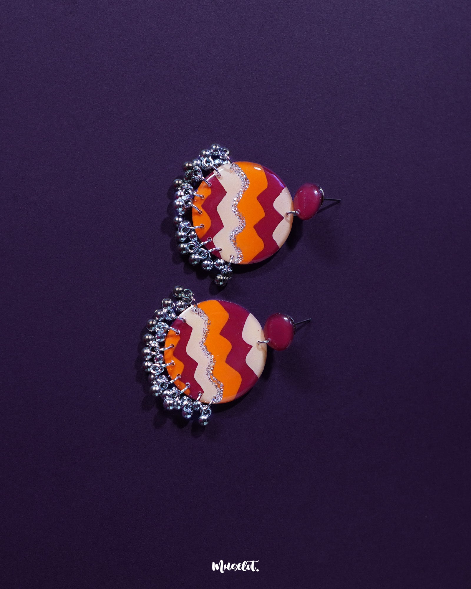 Close-up of a model wearing the Sahar traditional stud earrings, showcasing the earthy mustard and rust color palette with silver detailing and hanging ghungroos that add a soft, ethnic charm — Muselot.