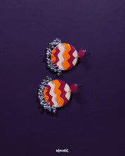 Close-up of a model wearing the Sahar traditional stud earrings, showcasing the earthy mustard and rust color palette with silver detailing and hanging ghungroos that add a soft, ethnic charm — Muselot.