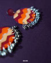 Close-up of the Sahar traditional stud earrings placed on a textured surface, showcasing their vibrant mustard and rust tones with ornate oxidized silver detailing and delicate ghungroo accents — Muselot.