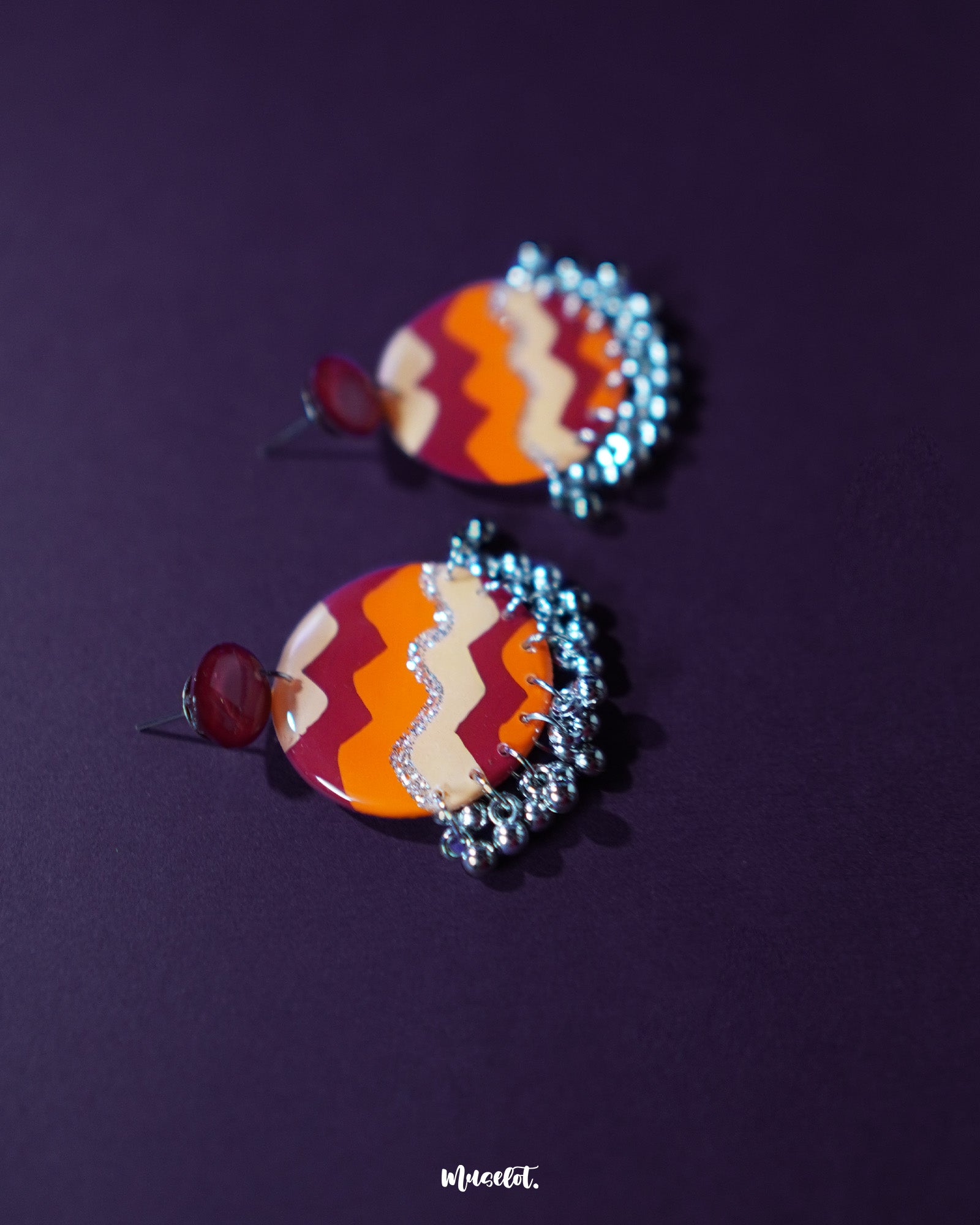 Sahar traditional stud earrings set against a deep purple backdrop, highlighting the intricate oxidized silver work, warm yellow and rust enamel accents, and charming ghungroo details that give a festive touch — Muselot.