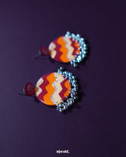 Sahar traditional stud earrings set against a deep purple backdrop, highlighting the intricate oxidized silver work, warm yellow and rust enamel accents, and charming ghungroo details that give a festive touch — Muselot.