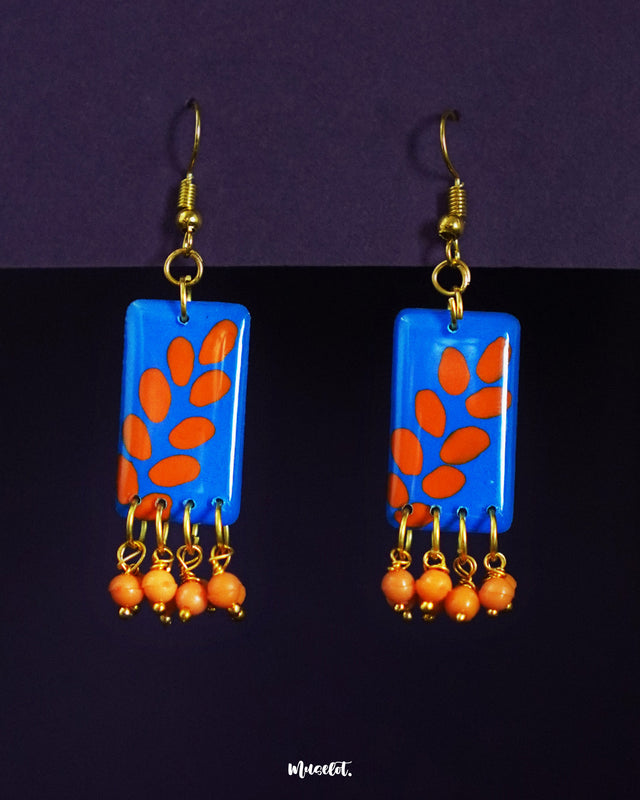 Sandhyaraag boho drop earrings highlighting bold orange petal motifs on a vibrant blue base, showcasing their artsy charm and playful elegance with dangling orange beads — Muselot