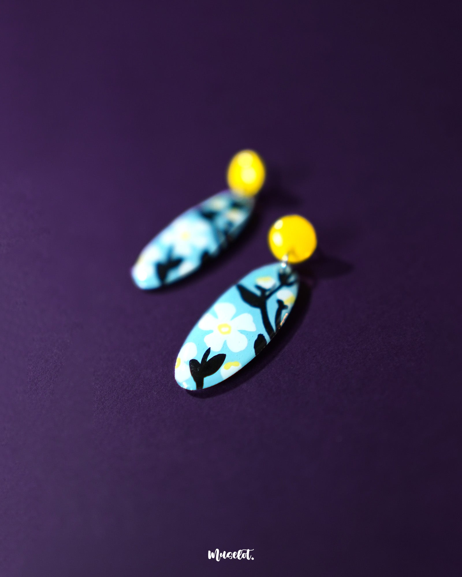 A pair of Shaamgul drop earrings displayed flat, showcasing the handcrafted floral elements and beadwork in a graceful, symmetrical layout — Muselot.