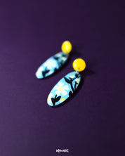 A pair of Shaamgul drop earrings displayed flat, showcasing the handcrafted floral elements and beadwork in a graceful, symmetrical layout — Muselot.