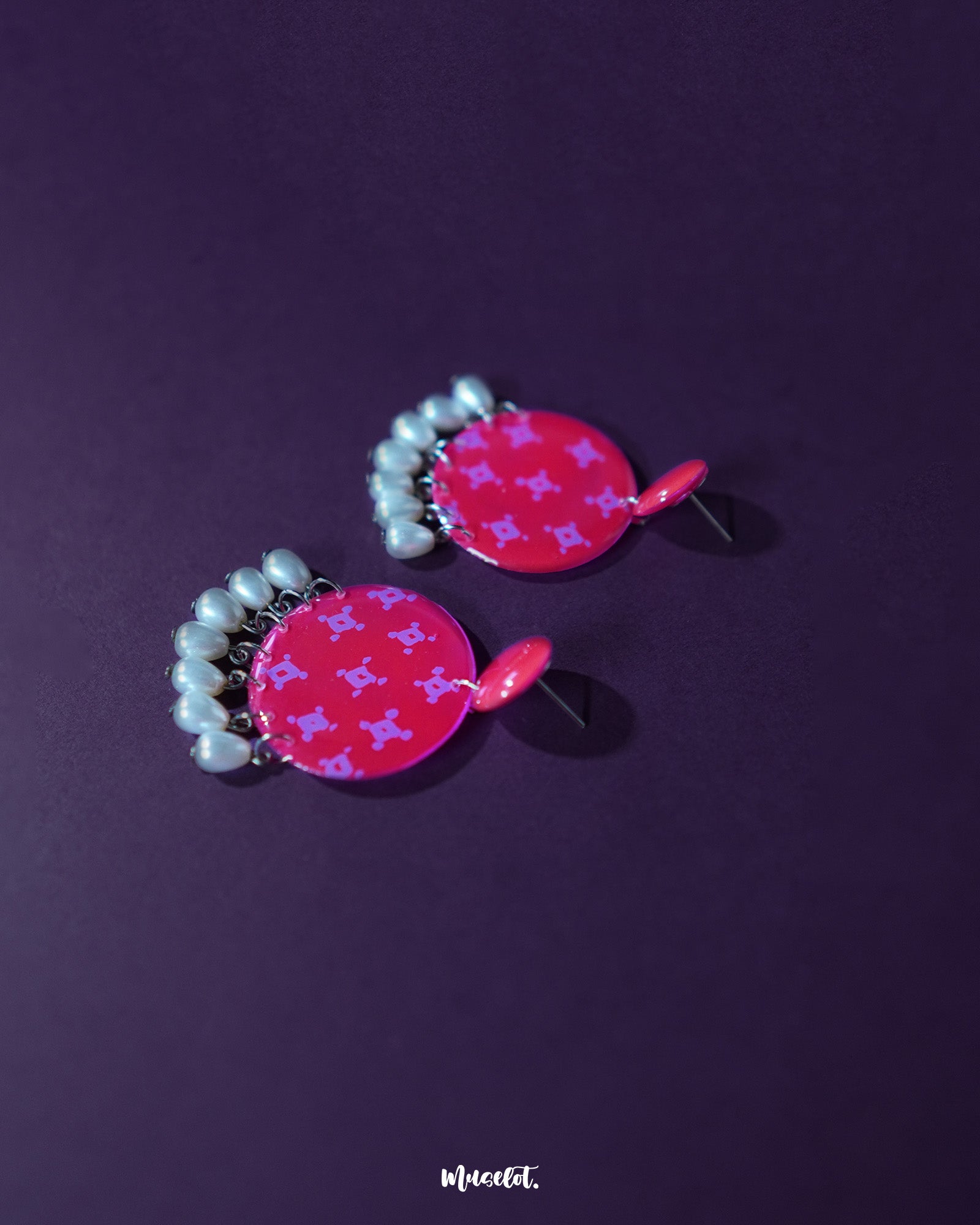 Shabnam pink pearl drop earrings placed flat against a neutral surface, showcasing the soft pink dome-shaped studs paired with glossy pearl-like drops, highlighting their dainty craftsmanship and elegant finish — Muselot.