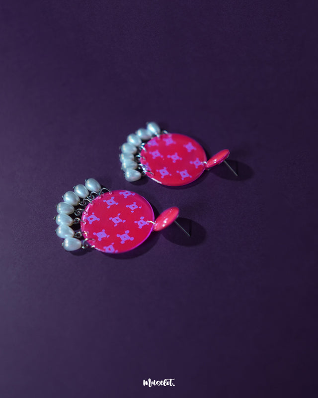 Shabnam pink pearl drop earrings placed flat against a neutral surface, showcasing the soft pink dome-shaped studs paired with glossy pearl-like drops, highlighting their dainty craftsmanship and elegant finish — Muselot.