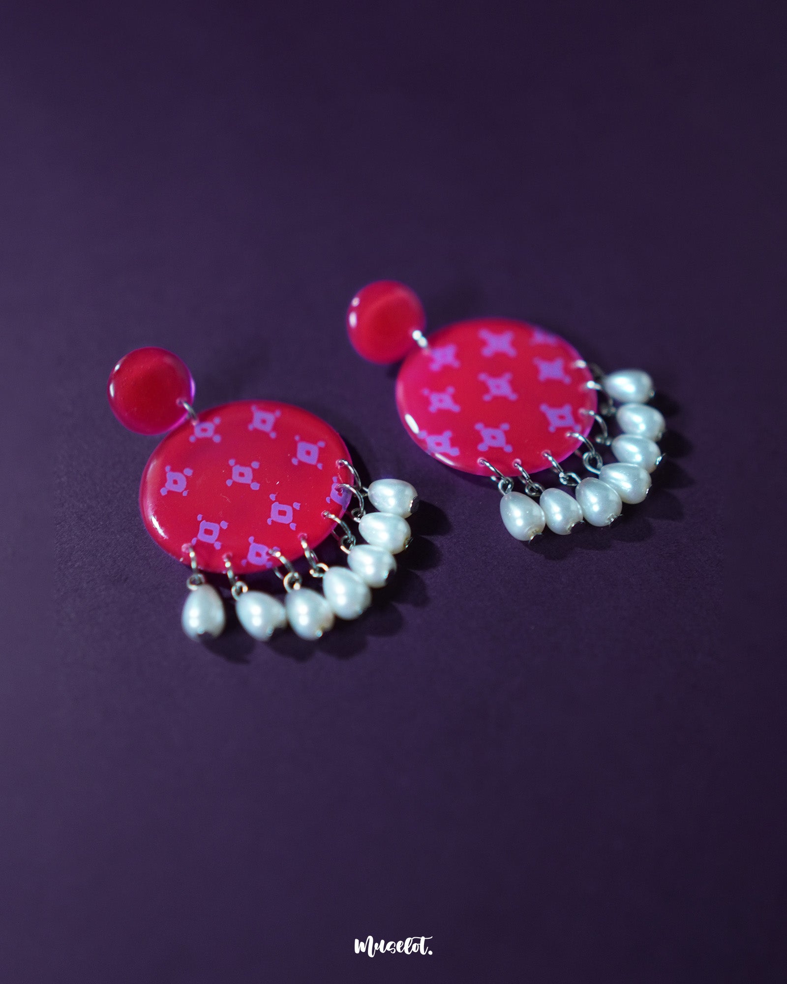 Close-up of the Shabnam pink pearl drop earrings on a textured surface, showcasing the gentle sheen of the pink dome studs and the smooth, dangling pearls beneath, highlighting their soft feminine appeal and handcrafted detailing — Muselot.
