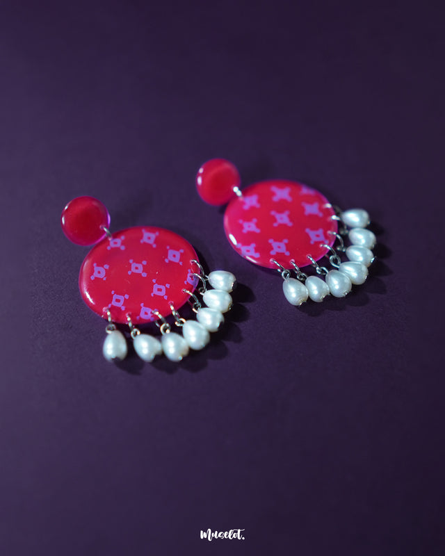 Close-up of the Shabnam pink pearl drop earrings on a textured surface, showcasing the gentle sheen of the pink dome studs and the smooth, dangling pearls beneath, highlighting their soft feminine appeal and handcrafted detailing — Muselot.