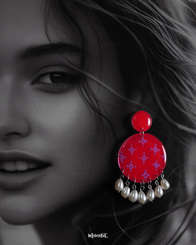 A zoom in shot of a woman wearing the Shabnam stud drop earrings, featuring bright pink circular studs adorned with subtle lavender patterns and elegant pearl-like drops, showcasing festive charm and highlighting handcrafted elegance — Muselot.