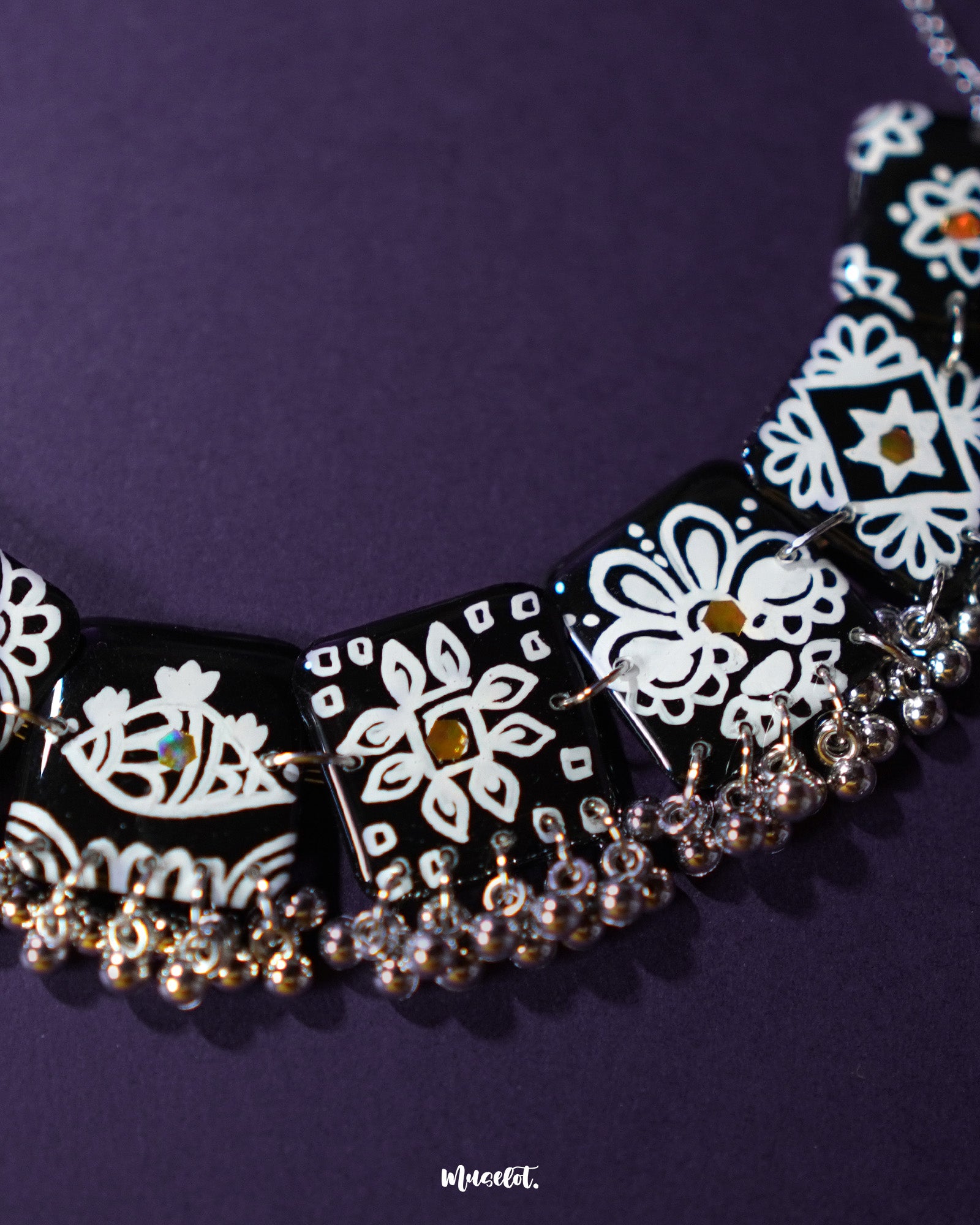 The Shabnoor black floral jewelry set laid out on a soft cream background, highlighting the intricate black floral motifs and the cohesive elegance of the handcrafted necklace and matching earrings — Muselot.
