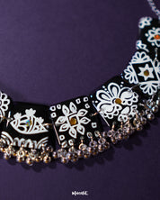 The Shabnoor black floral jewelry set laid out on a soft cream background, highlighting the intricate black floral motifs and the cohesive elegance of the handcrafted necklace and matching earrings — Muselot.