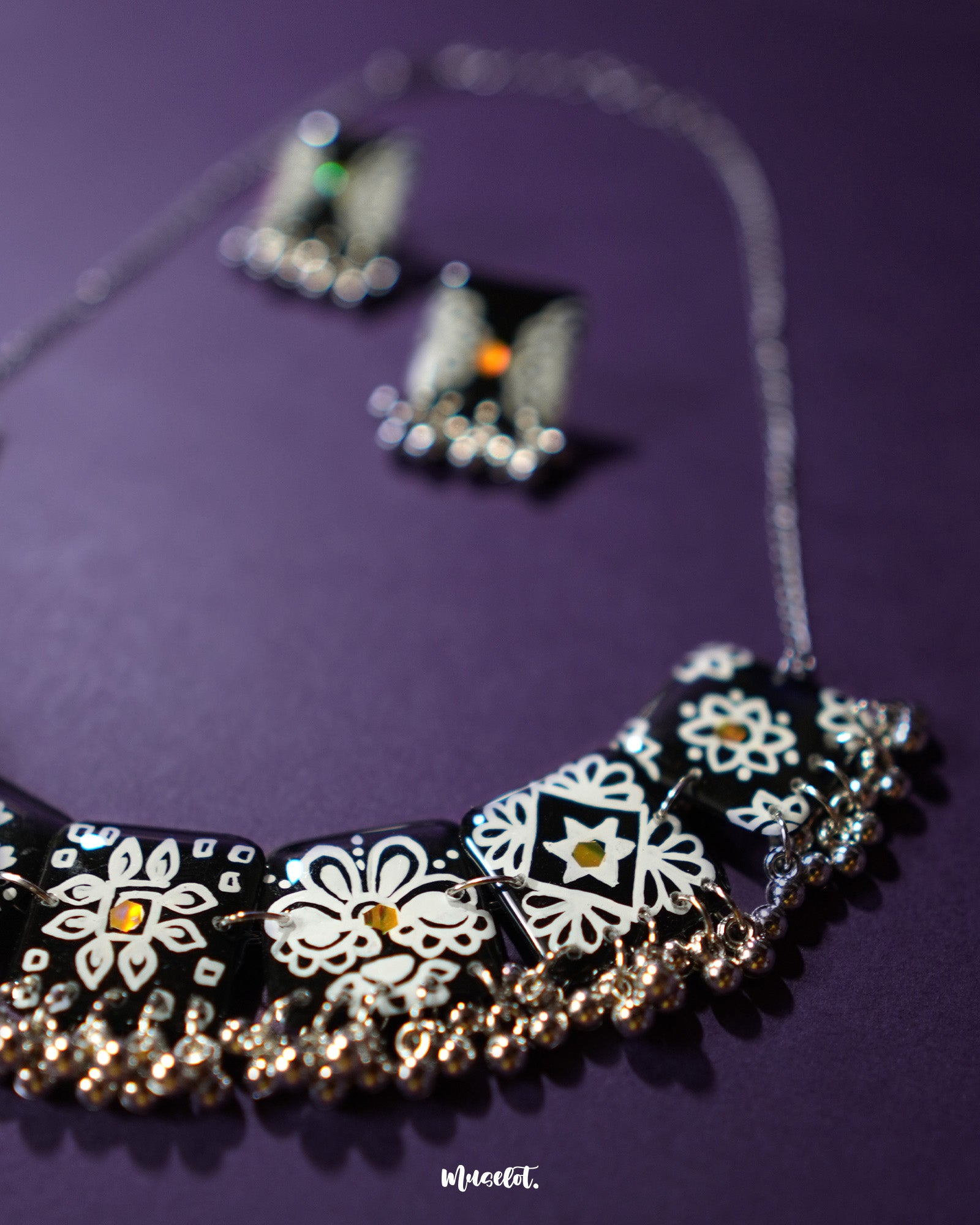 A black traditional jewelry set, highlighting the ornate design and textured craftsmanship of the beads and floral motifs against a soft background — Muselot.
