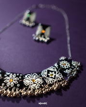 A black traditional jewelry set, highlighting the ornate design and textured craftsmanship of the beads and floral motifs against a soft background — Muselot.