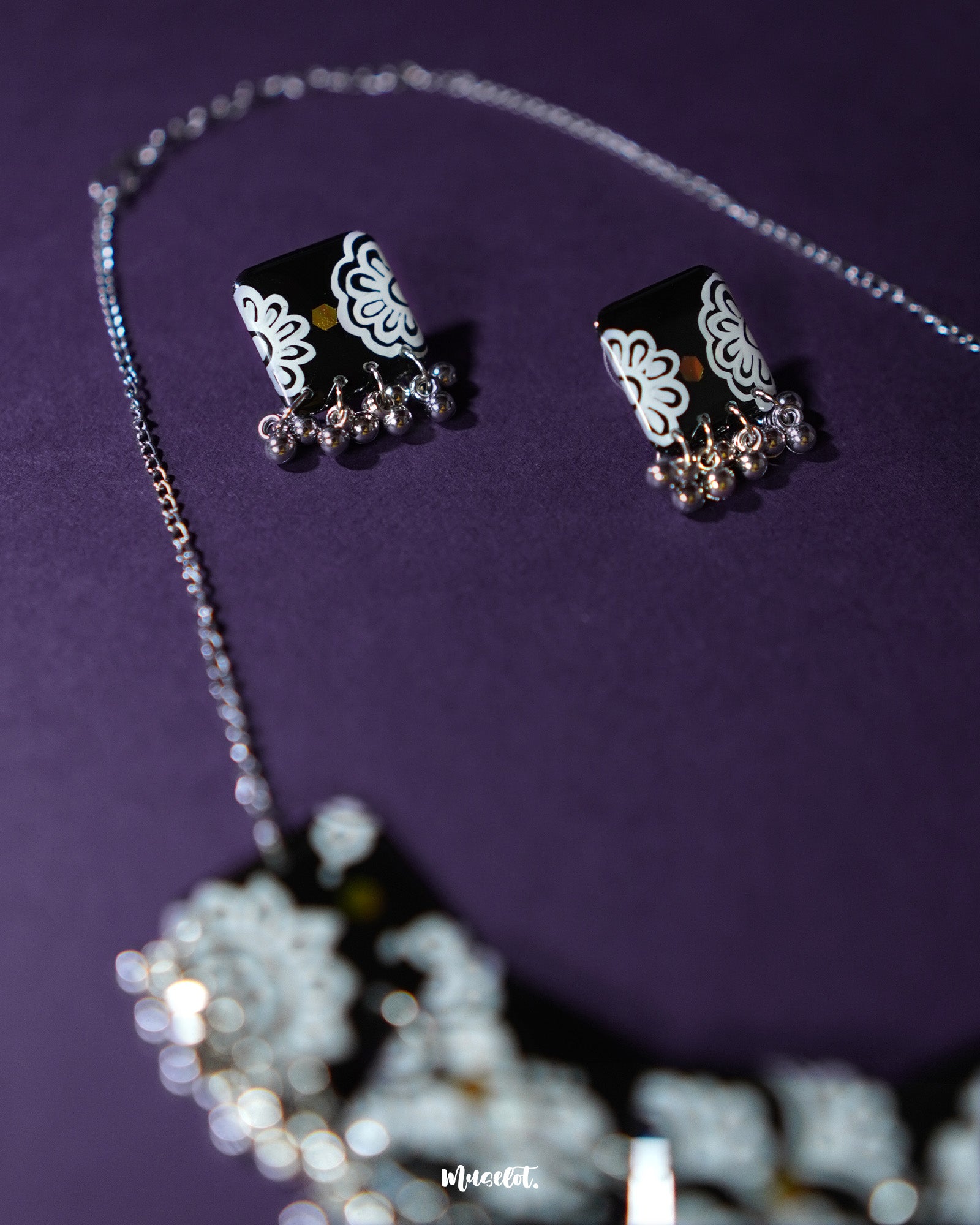 A detailed close-up of Shabnoor black floral earrings from the jewelry set, highlighting the delicate craftsmanship and elegant black floral design that adds a timeless touch — Muselot.